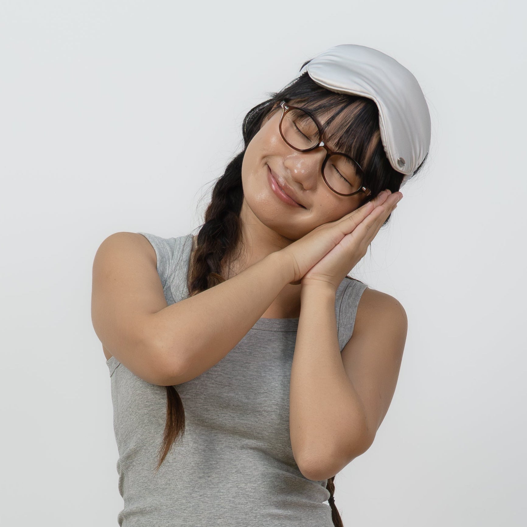 A woman posing in a grey sleeveless top, a white tiered ruffle mini skirt, white socks, and a white cap against a plain white wall and light wood floor.